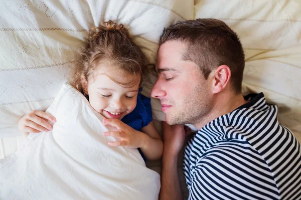 Father and daughter lying in parents bed, sleeping, smiling — Stock Photo, Image