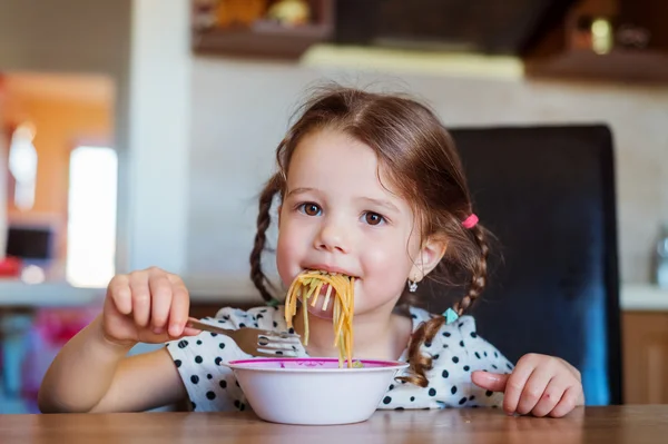 Lilla flickan i köket leende, äta spaghetti — Stockfoto