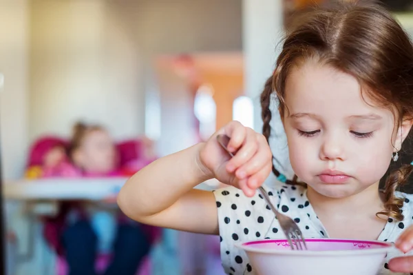 Niña en la cocina sonriendo, comiendo espaguetis — Foto de Stock