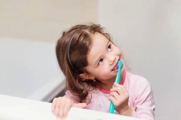 Petite fille en pyjama rose dans la salle de bain brossant les dents — Photo