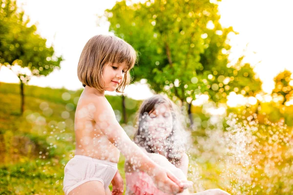 Zwei Mädchen bei Sprinkleranlage im Garten — Stockfoto
