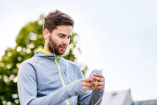 Jonge atleet in de stad met smartphone — Stockfoto