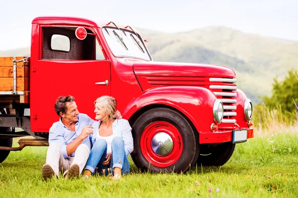 Seniorenpaar bei rotem Oldtimer — Stockfoto