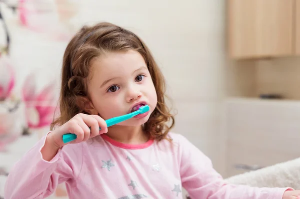 Niña en pijama rosa en baño cepillándose los dientes —  Fotos de Stock