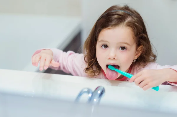 Niña en pijama rosa en baño cepillándose los dientes — Foto de Stock