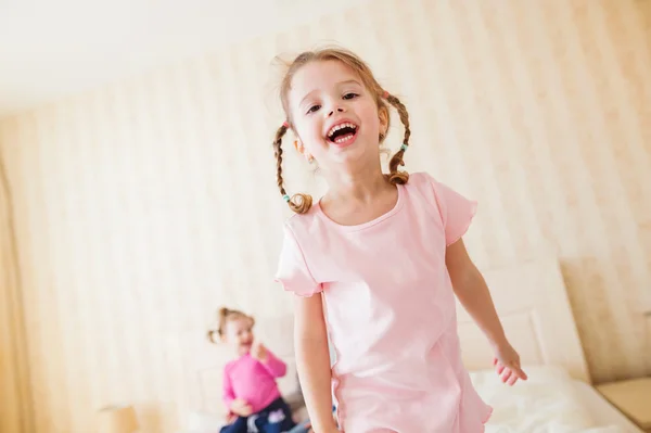 Deux petites filles dans la chambre à coucher sautant sur un lit — Photo