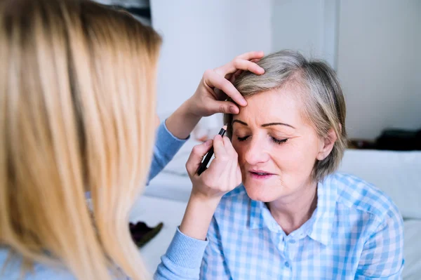 Chica irreconocible aplicando maquillaje a una mujer mayor — Foto de Stock