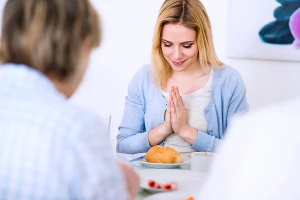 Young woman praying before having meal with her family. — Φωτογραφία Αρχείου