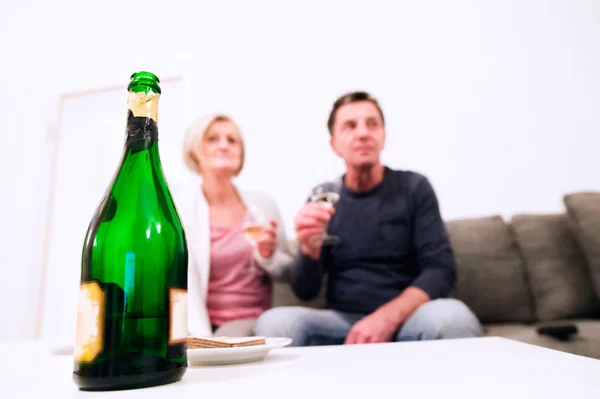 Casal de idosos sentado na sala de estar, bebendo champanhe — Fotografia de Stock