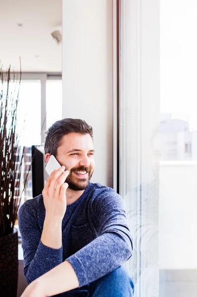 Empresario trabajando desde casa, sosteniendo el teléfono inteligente haciendo teléfono c —  Fotos de Stock