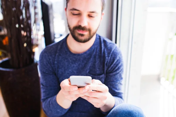 Hipster businessman working from home, holding smartphone, texti — Stock Photo, Image