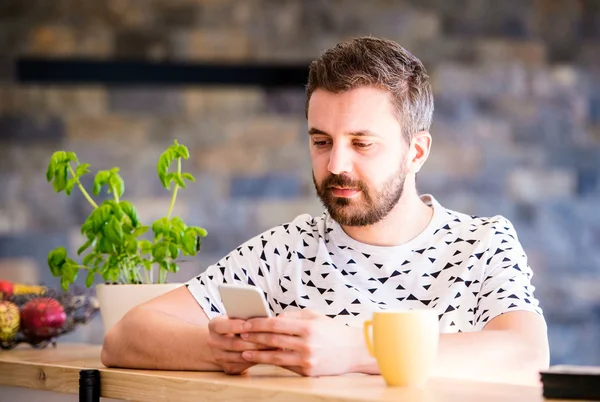 Hipster businessman working from home, holding smartphone, texti — Stock Photo, Image