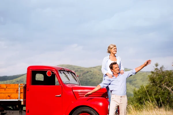 Äldre par stående på den röda vintage bil — Stockfoto