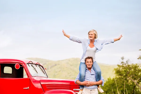 Äldre par stående på den röda vintage bil — Stockfoto