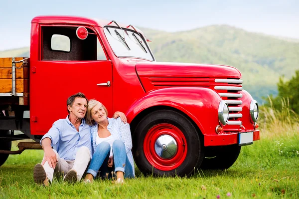 Senior para siedzi na czerwony samochód rocznika — Zdjęcie stockowe