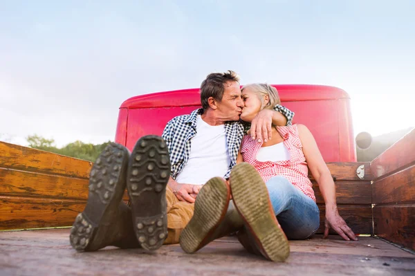 Senior paar zitten achterkant rode pick-up — Stockfoto