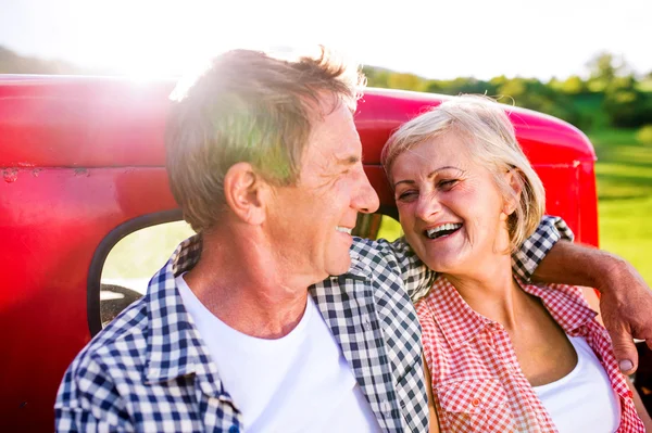 赤いピックアップ トラックの後ろに座っている年配のカップル — ストック写真