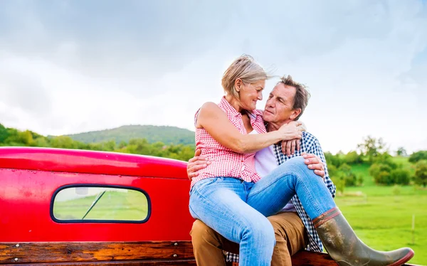 Senior paar zitten achterkant rode pick-up — Stockfoto