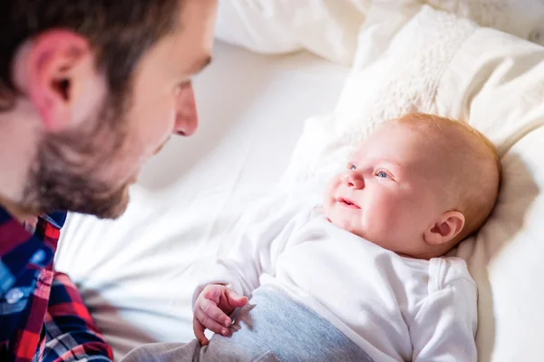 Vader met baby jongen op bed — Stockfoto