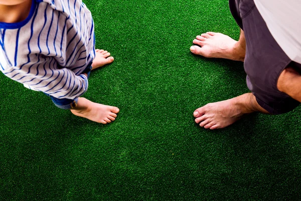 Pai e filho em pé na grama artificial — Fotografia de Stock