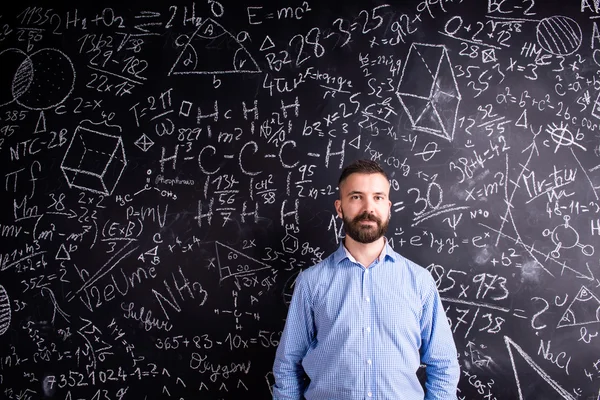 Teacher at blackboard with mathematical symbols — Stock Photo, Image