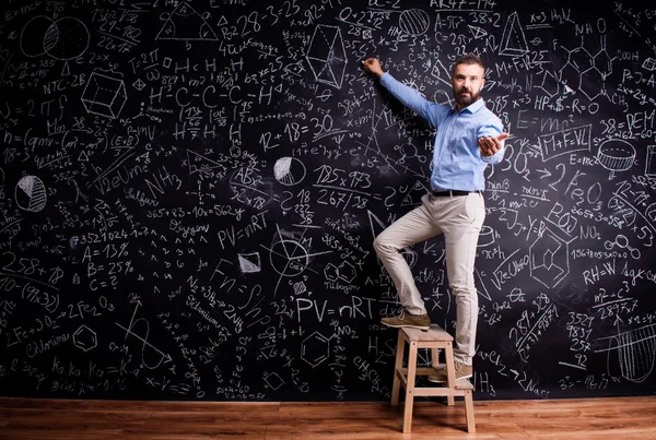 Человек, пишущий на доске с математическими символами — стоковое фото