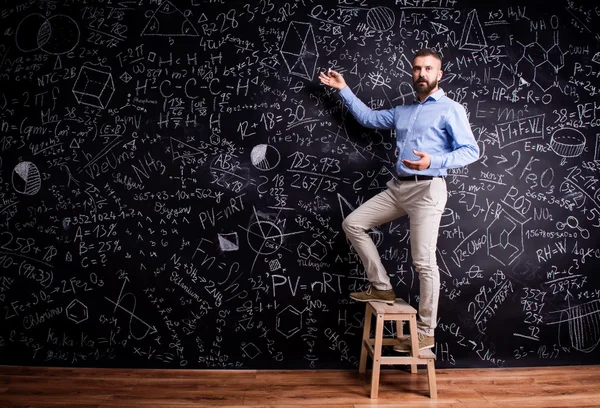 Man writing on blackboard with mathematical symbols — Stock Photo, Image