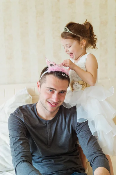 Pequeña niña poniendo corona en su padre —  Fotos de Stock