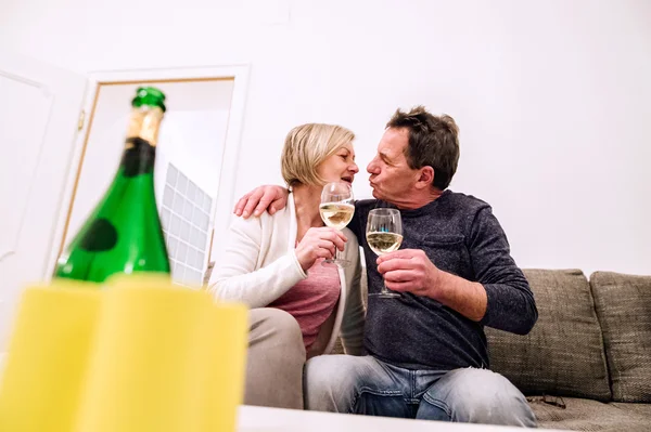 Seniorenpaar sitzt im Wohnzimmer, trinkt Champagner, küsst — Stockfoto