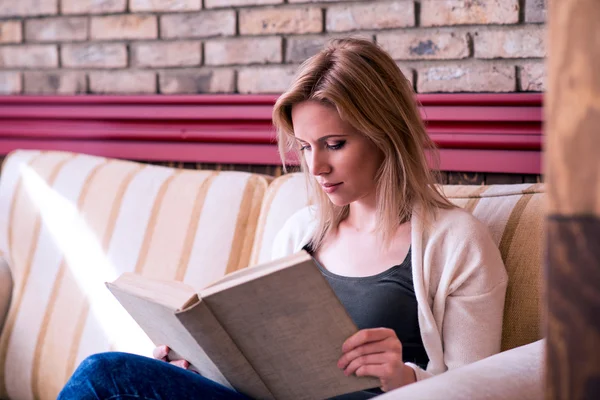 Blond woman with newspaper in cafe drinking coffee — Stock Photo, Image