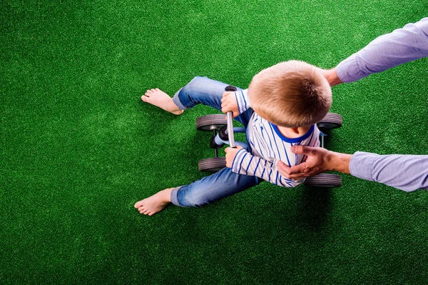 Pai irreconhecível segurando seu filho andando de bicicleta — Fotografia de Stock