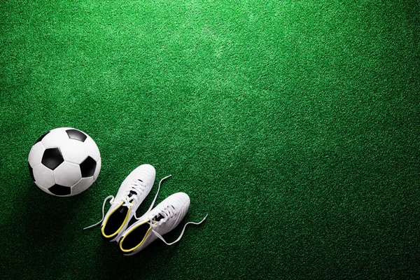 Bola de fútbol y tacos en césped artificial — Foto de Stock