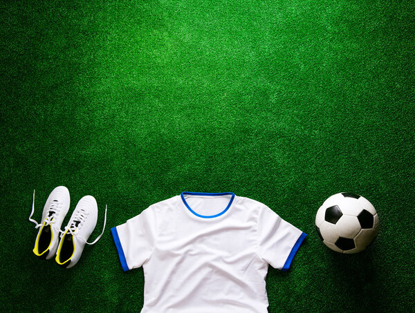 Soccer ball,cleats and white t-shirt against artificial turf