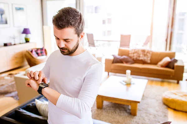 Man aan het werk vanuit huis met behulp van slimme horloge, woonkamer — Stockfoto