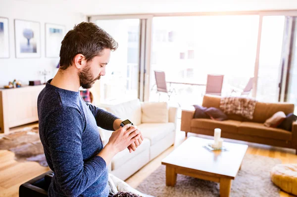 Hombre trabajando desde casa usando reloj inteligente, sala de estar —  Fotos de Stock