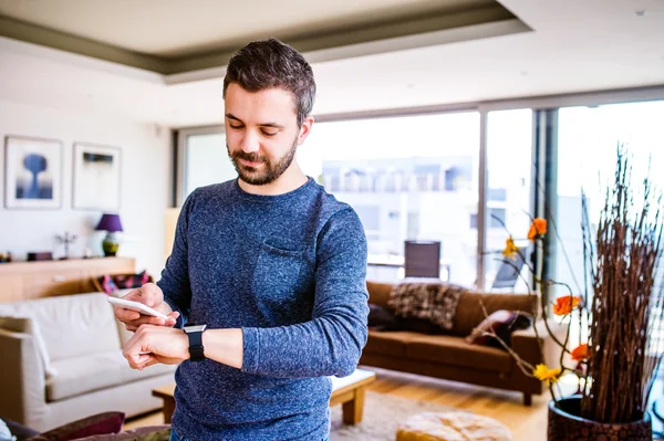Man som arbetar hemifrån med hjälp av smartphone och smart Watch-klocka — Stockfoto