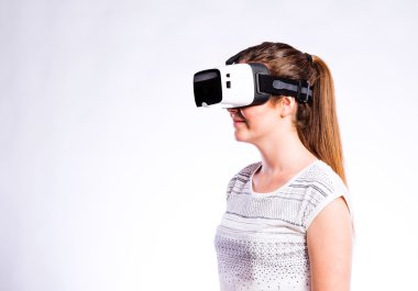 Sanal gerçeklik gözlüklü bir kadın. Stüdyo çekimi, gri arkaplan