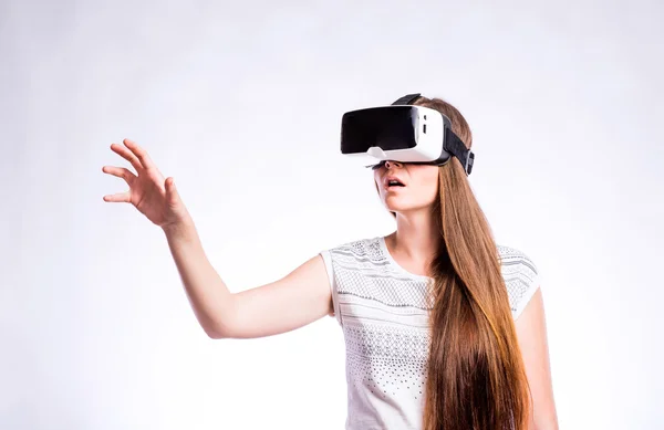 Egy nő virtuális valóság szemüveggel. Stúdió lövés, szürke háttér — Stock Fotó