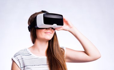 Sanal gerçeklik gözlüklü bir kadın. Stüdyo çekimi, gri arkaplan