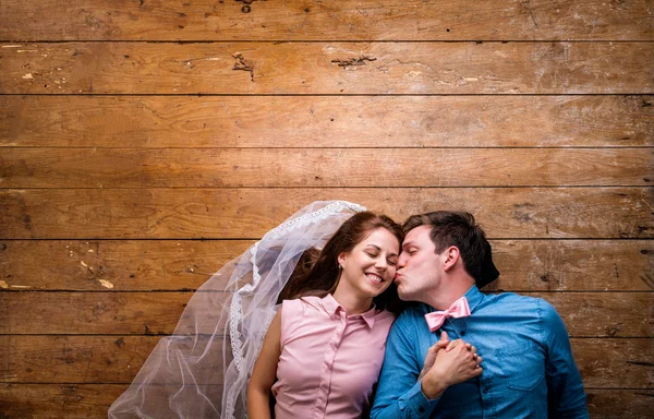 Pareja joven tumbada en el suelo sobre fondo de madera — Foto de Stock