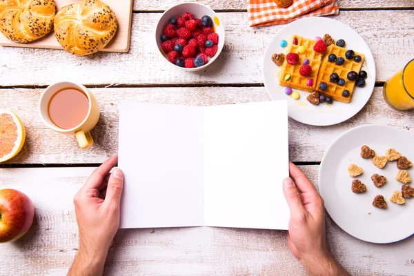 Hände eines Mannes, der eine leere Grußkarte hält. Frühstücksbuffet. — Stockfoto