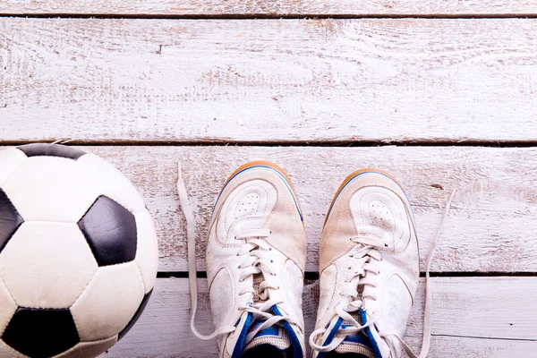 Bola de futebol, chuteiras no chão de madeira branco, tiro estúdio — Fotografia de Stock