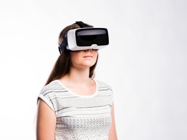 Sanal gerçeklik gözlüklü bir kadın. Stüdyo çekimi, gri arkaplan