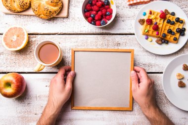 Boş resim çerçevesini tutan adamın elini. Kahvaltı yemek.
