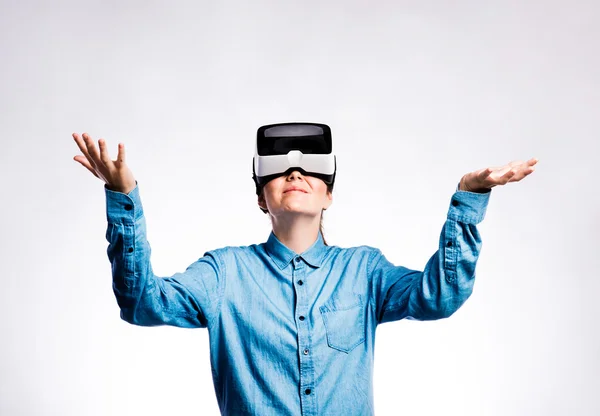 Žena s brýlemi pro virtuální realitu. Studio záběr, šedé pozadí — Stock fotografie
