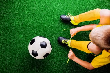 Tanınmayan küçük futbol oyuncu yeşil çimen, studi karşı