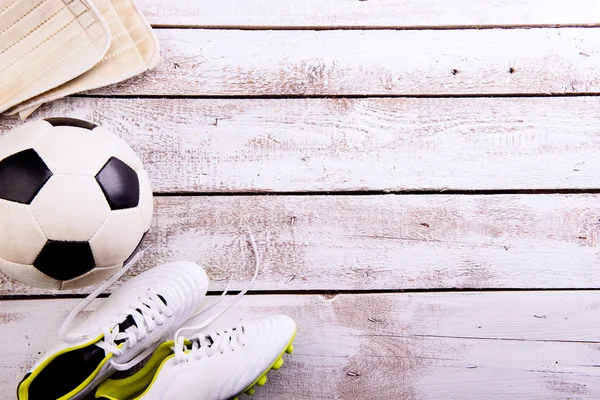 Soccer ball, cleats on white wooden floor, studio shot — Stock Photo, Image