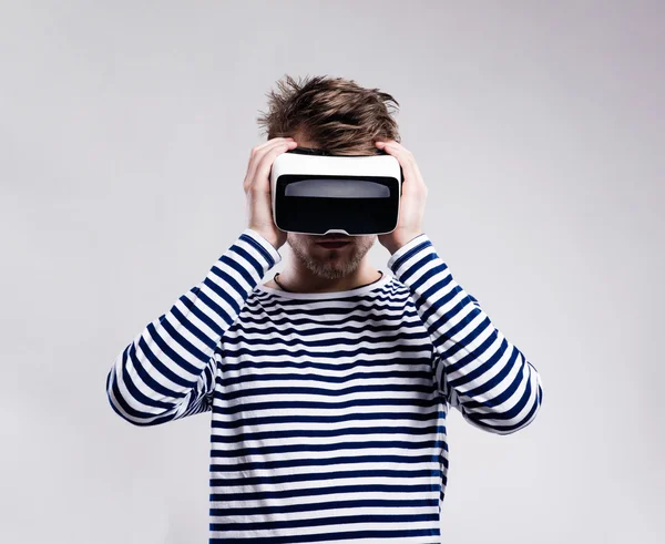 Man wearing virtual reality goggles. Studio shot, gray backgroun — Stock Photo, Image