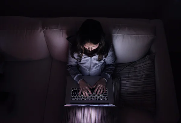 Niña, sentada en una oscuridad, jugando con el portátil — Foto de Stock