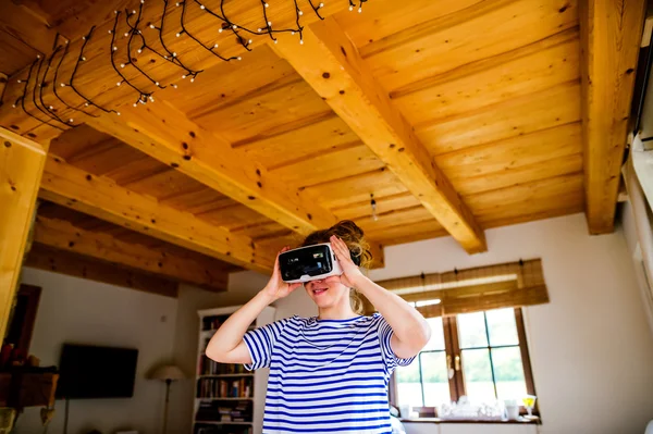 Kobieta ubrana wirtualnej rzeczywistości gogle stoi w salonie — Zdjęcie stockowe